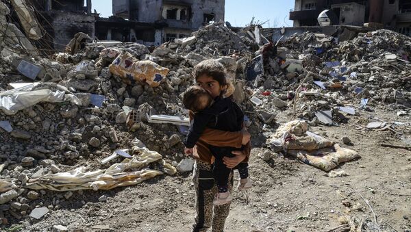 Children walk among the rubble of damaged buildings following heavy fighting between government troops and Kurdish fighters in the Kurdish town of Cizre in southeastern Turkey, which lies near the border with Syria and Iraq, on March 2, 2016. - Sputnik Afrique