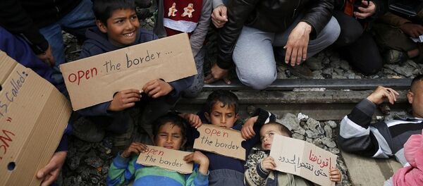 Migrants hold posters as they block the railway track at the Greek-Macedonian border - Sputnik Afrique