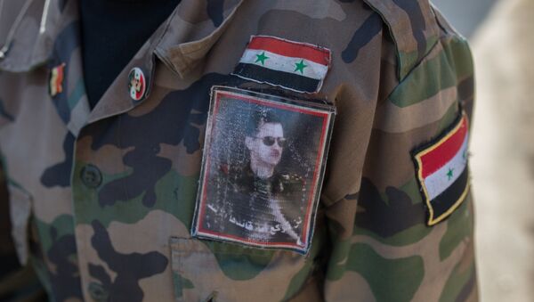 Un volontaie de l'armée syrienne porte un uniforme à l'effigie du président Assad - Sputnik Afrique