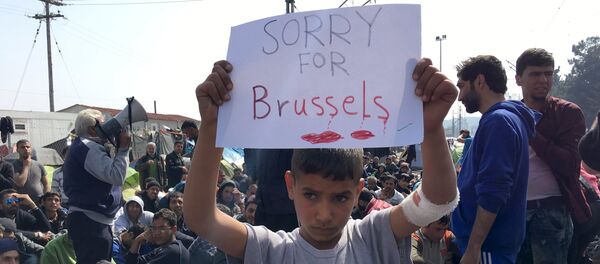 A refugee boy holds up a placard reading Sorry for Brussels as refugees and migrants take part in a protest against the closure of the border at the Greek-Macedonian border March 22, 2016, near the Greek village of Idomeni. - Sputnik Afrique