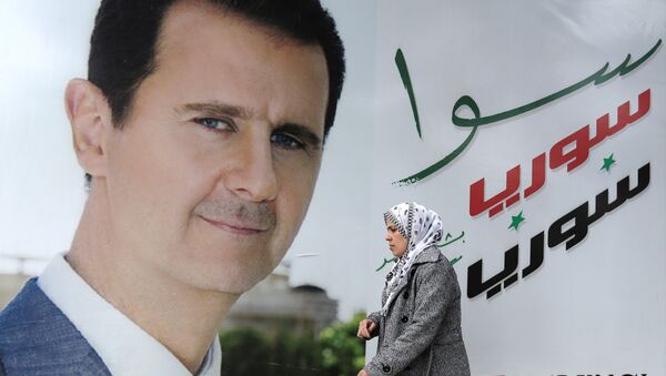 A Syrian woman walks past a placard bearing a portrait of President Bashar al-Assad in the city of Damascus on March 4, 2015. AFP PHOTO / LOUAI BESHARA - Sputnik Afrique