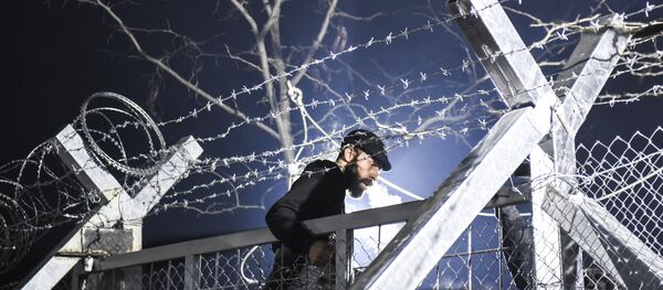 A migrant stands on a border gate as he and other migrants and refugees try to cross the Greek-Macedonian border near the village of Idomeni, Greece, on December 3, 2015. - Sputnik Afrique