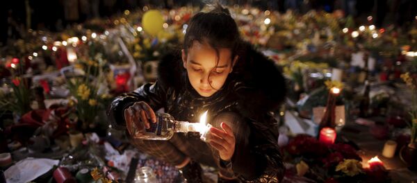 A girl lights candles as people pay tribute to the victims of Tuesday's bomb attacks, at the Place de la Bourse in Brussels, Belgium, March 26, 2016. - Sputnik Afrique