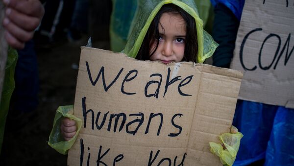A girl holds a placard during a protest held by migrants and refugees to call for the reopening of the borders at a makeshift camp at the Greek-Macedonian border near the village of Idomeni on March 23, 2016. - Sputnik Afrique