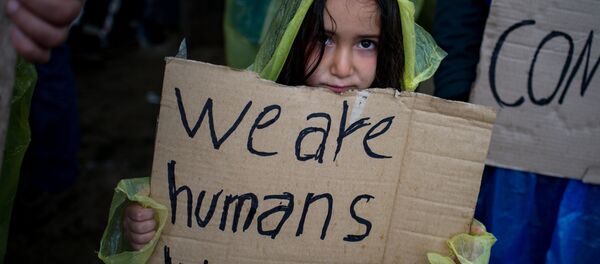 A girl holds a placard during a protest held by migrants and refugees to call for the reopening of the borders at a makeshift camp at the Greek-Macedonian border near the village of Idomeni on March 23, 2016. - Sputnik Afrique