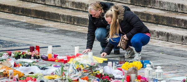 Two women read a solidarity message at floral tributes at a memorial site at the Place de la Bourse in Brussels, Sunday, March 27, 2016. - Sputnik Afrique
