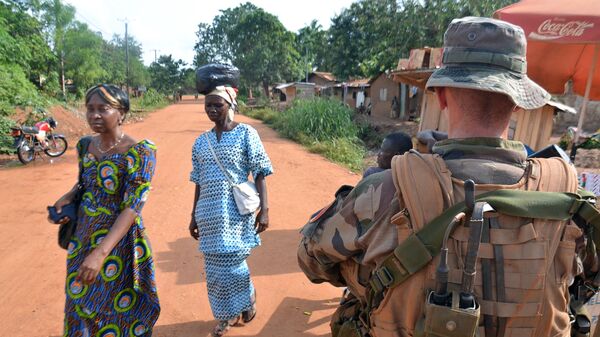Women walk past a French soldier, part of Operation Sangaris, on patrol in the 6th district of the capital Bangui, on May 20, 2015. - Sputnik Afrique
