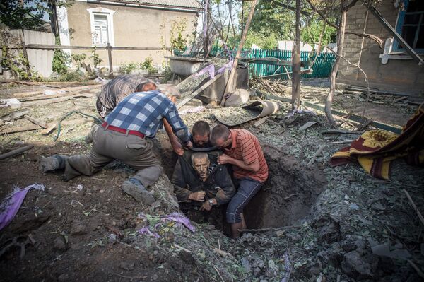 Trois jours avant le silence - Les habitants locaux retirent le corps d'un homme tué lors des tirs d'artillerie dans le village d'Alexandrovka, dans la région de Donetsk Trois jours avant le silence - Les habitants locaux retirent le corps d'un homme tué lors des tirs d'artillerie dans le village d'Alexandrovka, dans la région de Donetsk - Sputnik Afrique