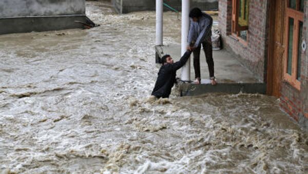 Un homme kashmirien tend la main pour aider une évacuer locale d'une zone touchée par les inondations à Srinagar, au Cachemire sous contrôle indien - Sputnik Afrique
