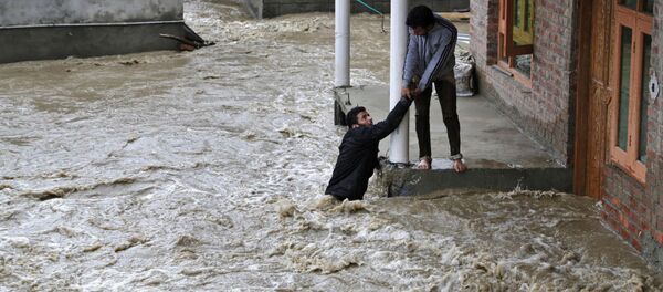 Un homme kashmirien tend la main pour aider une évacuer locale d'une zone touchée par les inondations à Srinagar, au Cachemire sous contrôle indien - Sputnik Afrique