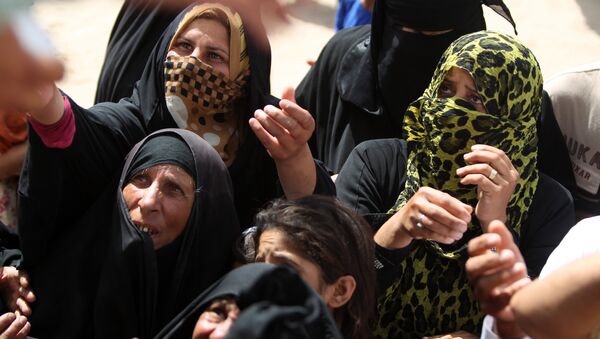 Displaced Iraqi women, who fled Ramadi, the capital of Anbar province, after it was seized by the Islamic State (IS) group, wait to get aid boxes at a makeshift camp for internally displaced persons (IDP) in Ameriyat al-Fallujah, 30 km south of Fallujah on June 6, 2015 - Sputnik Afrique