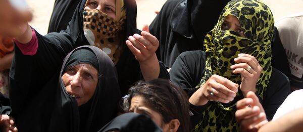 Les femmes irakiennes qui ont fui Ramadi, la capitale de la province d'Anbar, après qu'elle a été occupée par l'Etat islamique, attendent d'obtenir des boîtes d'aide humanitaire dans un camp à Ameriyat al-Falloujah, 30 km au sud de Falloujah le 6 Juin, 2015 - Sputnik Afrique