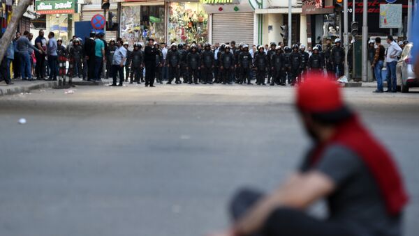 An Egyptian protester sits on the ground in front of riot policemen during a demonstration against a controversial deal to hand two islands in the Red Sea to Saudi Arabia on April 15, 2016 outside the Journalists' Syndicate in central Cairo. - Sputnik Afrique