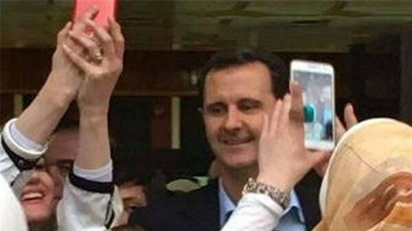 Des Syriens photographient le président Assad Des Syriens photographient le président Assad - Sputnik Afrique