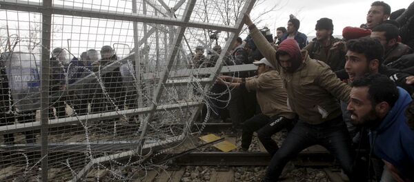 Stranded refugees and migrants try to bring down part of the border fence during a protest at the Greek-Macedonian border, near the Greek village of Idomeni, February 29, 2016 Stranded refugees and migrants try to bring down part of the border fence during a protest at the Greek-Macedonian border, near the Greek village of Idomeni, February 29, 2016 - Sputnik Afrique
