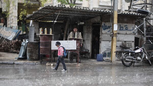 Un écolier syrien marche sous la pluie à Kafr Batna, dans la région de Ghouta orientale, à la périphérie de la capitale Damas (File) - Sputnik Afrique