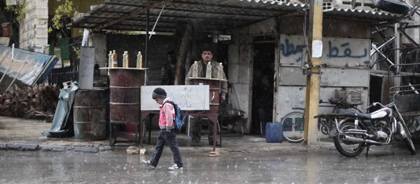 Un écolier syrien marche sous la pluie à Kafr Batna, dans la région de Ghouta orientale, à la périphérie de la capitale Damas (File) - Sputnik Afrique