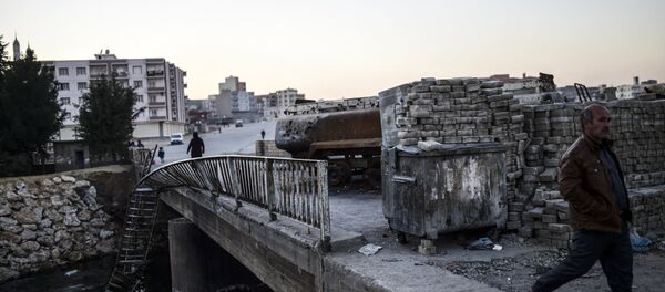 People walk past a burned truck at the entrance of Nusaybin on December 24, 2015, in Mardin - Sputnik Afrique
