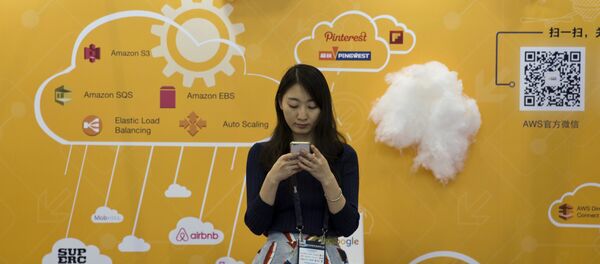 A woman uses her smartphone near a booth promoting cloud services during the Global Mobile Internet Conference in Beijing, China, Friday, April 29, 2016. - Sputnik Afrique