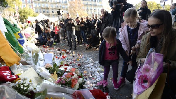 People place flowers and candles along a police cordon set-up close to the Bataclan concert hall on November 15, 2015 in Paris, following a series of coordinated attacks in and around Paris on November 13. - Sputnik Afrique