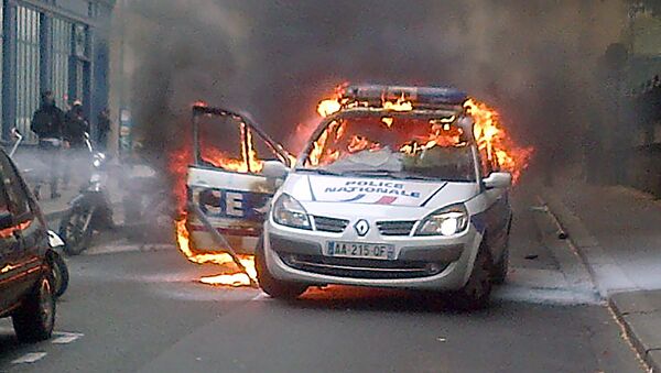 This picture taken with a mobile phone shows a police car burning after being set on fire during an unauthorized counter-demonstration against police violence on May 18, 2016 in Paris, as Police across France demonstrate today against the anti-cop hatred they say they have endured during a wave of anti-government protests since early March. - Sputnik Afrique