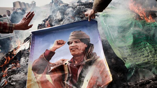 Un habitant de Benghazi (Libye) brûlant un portrait de Mouammar Kadhafi - Sputnik Afrique