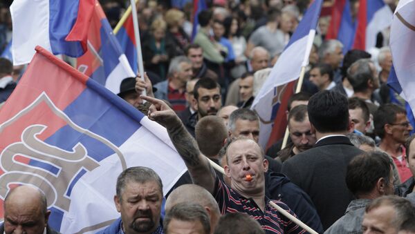Un Serbe bosniaque porte le drapeaux lors d'une manifestation à Banja Luka, en Bosnie, le samedi 14 mai 2016 - Sputnik Afrique