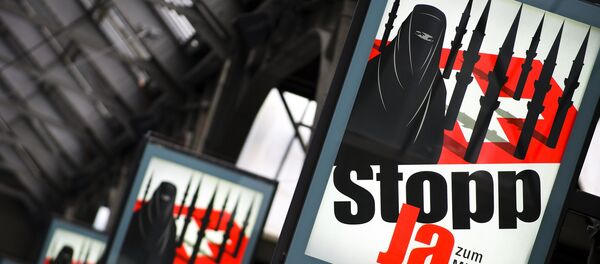 Campaign posters of the far-right Swiss People's Party depicting a woman wearing a burqa against a background of a Swiss flag upon which several minarets resembling missiles reading in German 'Stop - Yes to ban of minarets' are pictured on October 26, 2009 at the central station in Zurich. - Sputnik Afrique