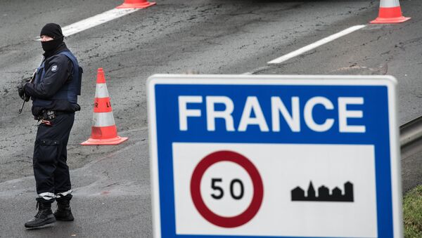 An armed policeman stands guard as other policemn check motorists' identities as part of security measures set following terrorist attacks in Paris on November 17, 2015 at the French-Belgium border in Neuville-en-Ferrain. - Sputnik Afrique