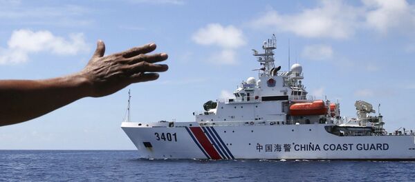 In this photo taken March 29, 2014, Philippines navy personnel motions towards a Chinese Coast Guard to make way as they block them from entering Second Thomas Shoal in the South China Sea. - Sputnik Afrique