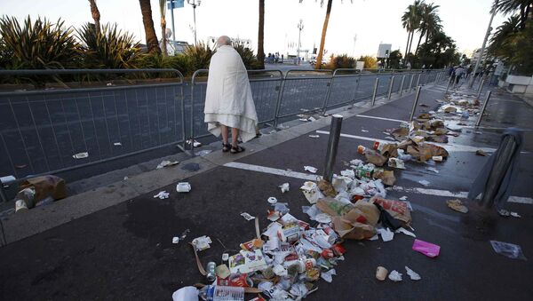 A man walks through debris scatterd on the street the day after a truck ran into a crowd at high speed killing scores celebrating the Bastille Day July 14 national holiday on the Promenade des Anglais in Nice, France, July 15, 2016. - Sputnik Afrique