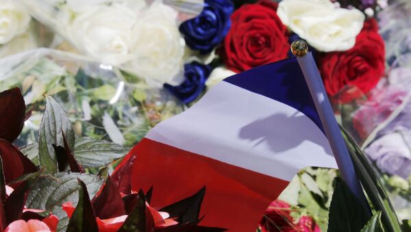 A bouquet of flowers and a French flag is seen as people pay tribute near the scene where a truck ran into a crowd at high speed killing scores and injuring more who were celebrating the Bastille Day national holiday, in Nice, France, July 15, 2016. - Sputnik Afrique