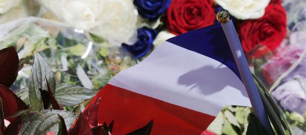 A bouquet of flowers and a French flag is seen as people pay tribute near the scene where a truck ran into a crowd at high speed killing scores and injuring more who were celebrating the Bastille Day national holiday, in Nice, France, July 15, 2016. - Sputnik Afrique