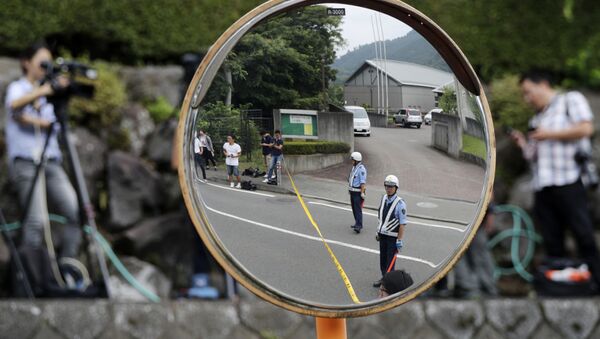 Police officers standing guard are reflected on a road mirror near the Tsukui Yamayuri-en, a facility for the handicapped, where a number of people were killed and dozens injured in a knife attack in Sagamihara, outside of Tokyo, Japan, Tuesday, July 26, 2016. - Sputnik Afrique