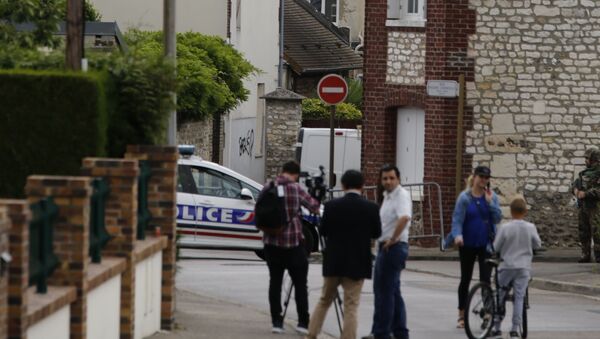 This photo taken on July 26, 2016 shows behind the church ofSaint-Etienne-du-Rouvray, blocked by police following an attack by two knife-wielding men. French President Francois Hollande that two men who attacked a church and slit the throat of a priest had claimed to be from Daesh, using the Arabic name for the Islamic State group. - Sputnik Afrique