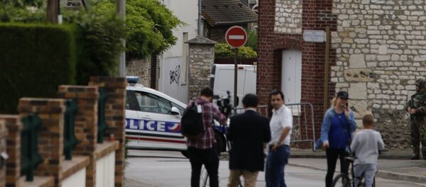 This photo taken on July 26, 2016 shows behind the church ofSaint-Etienne-du-Rouvray, blocked by police following an attack by two knife-wielding men. French President Francois Hollande that two men who attacked a church and slit the throat of a priest had claimed to be from Daesh, using the Arabic name for the Islamic State group. - Sputnik Afrique