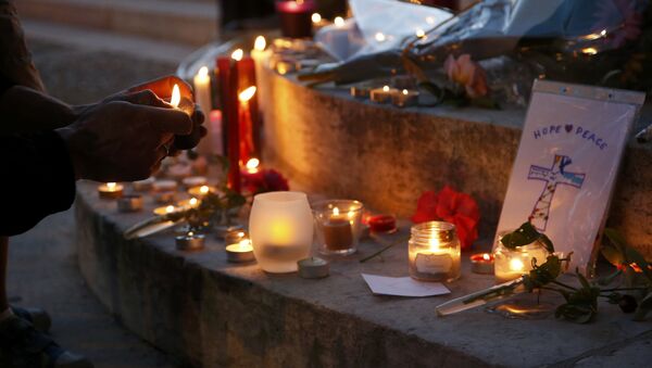 A woman lights a candle to place with flowers and candles at the town hall in Saint-Etienne-du-Rouvray, near Rouen in Normandy, France, to pay tribute to French priest, Father Jacques Hamel, who was killed with a knife and another hostage seriously wounded in an attack on a church that was carried out by assailants linked to Islamic State, July 26, 2016. - Sputnik Afrique