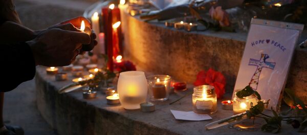 A woman lights a candle to place with flowers and candles at the town hall in Saint-Etienne-du-Rouvray, near Rouen in Normandy, France, to pay tribute to French priest, Father Jacques Hamel, who was killed with a knife and another hostage seriously wounded in an attack on a church that was carried out by assailants linked to Islamic State, July 26, 2016. - Sputnik Afrique