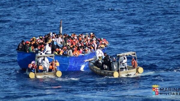 Migrants sit in their boat during a rescue operation by Italian navy ship Borsini (unseen) off the coast of Sicily, Italy, in this handout picture courtesy of the Italian Marina Militare released on July 19, 2016. - Sputnik Afrique