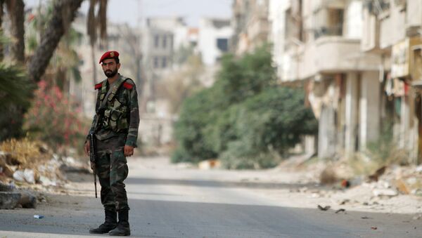 A Syrian army soldier stands at the entrance of the besieged Damascus suburb of Daraya, before the start of evacuation of residents and insurgents of Daraya, Syria August 26, 2016. REUTERS/Omar Sanadiki - Sputnik Afrique