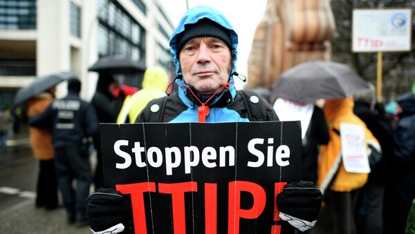 A protester holds up a sign, reading: Stop TTIP! (Transatlantic Trade and Investment Partnership) - Sputnik Afrique