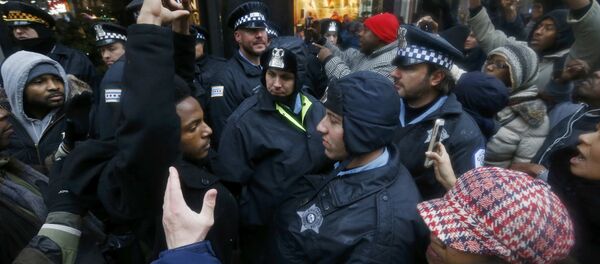 Demonstators hold their hands up in front of Chicago Police officers during protest of last year's shooting death of black teenager Laquan McDonald by a white policeman and the city's handling of the case in the downtown shopping district of Chicago, Illinois, November 27, 2015 - Sputnik Afrique