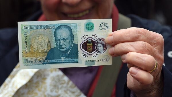A woman holds up a new £5 (6.5 euros, $7.2) banknote bearing the image of wartime leader Winston Churchill at its unveiling by the Bank of England at Blenheim Palace in Woodstock on June 2, 2016. - Sputnik Afrique