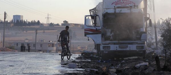 A boy rides a bicycle near a damaged aid truck after an airstrike on the rebel held Urm al-Kubra town, western Aleppo city, Syria September 20, 2016. - Sputnik Afrique