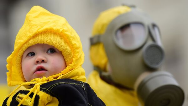 A child is pictured next to an anti-nuclear activist wearing a gas mask during a protest against the lack of safety of Belgian nuclear power plants, outside the Belgian Interior Ministry in Brussels, February 1, 2016, during a meeting of Germany's Environment Minister with Belgium's Interior Minister. - Sputnik Afrique