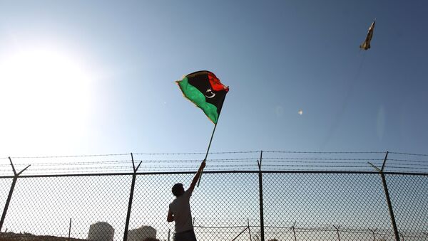 A man waves a Libyan flag as fighter jet flies by at the Zueitina oil terminal on September 14, 2016. - Sputnik Afrique