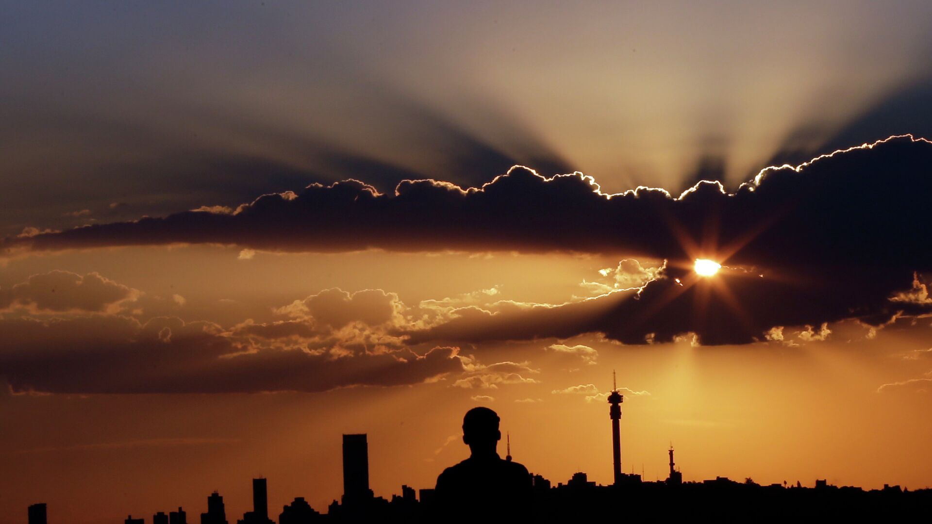 A man watches the sun set in as he overlooks the skyline in Johannesburg, South Africa. - Sputnik Africa, 1920, 16.12.2022