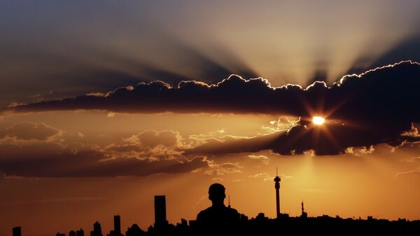 A man watches the sun set in as he overlooks the skyline in Johannesburg, South Africa. - Sputnik Africa