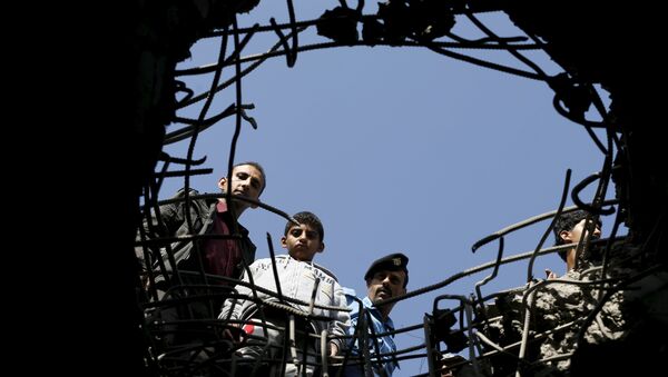 People and a policeman look through a hole caused by a Saudi-led air strike on a bridge in Yemen's capital Sanaa - Sputnik Afrique