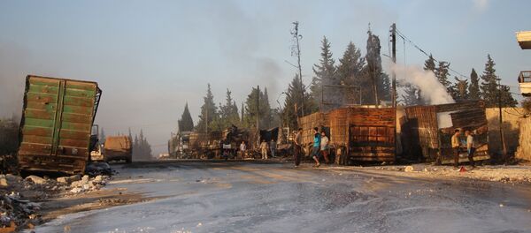 Syrians gather near damaged trucks carrying aid on the side of the road in the town of Orum al-Kubra on the western outskirts of the northern Syrian city of Aleppo on September 20, 2016, the morning after a convoy delivering aid was hit by a deadly air strike - Sputnik Afrique